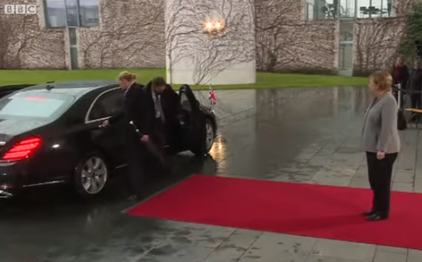 Сама на црвениот тепих: Тереза Меј остана заклучена во автомобилот, Меркел трпеливо ја чекаше